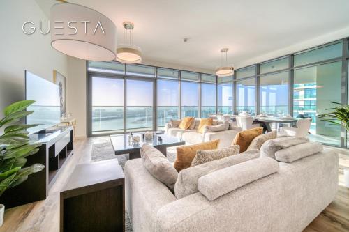 a living room with a large couch and glass windows at Emaar Beachfront - Beach Vista Tower, Dubai Marina in Dubai