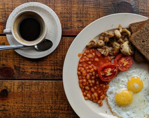 a plate of food with beans and a cup of coffee at Hhusha Hhusha in Malelane