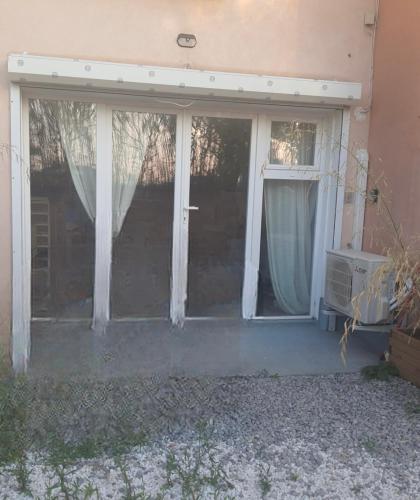 un porche grillagé d'une maison avec des rideaux blancs dans l'établissement Appartement T2 de 51m3 à Palavas-les-flots, à Palavas-les-Flots