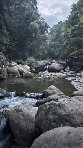 a person swimming in a river with rocks at Hidden Valley Wayanad in Meppādi