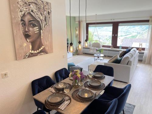a living room with a table and a painting of a woman at Cozy II Luxuriös Moselview Terrasse Garten NETFLIX in Leiwen