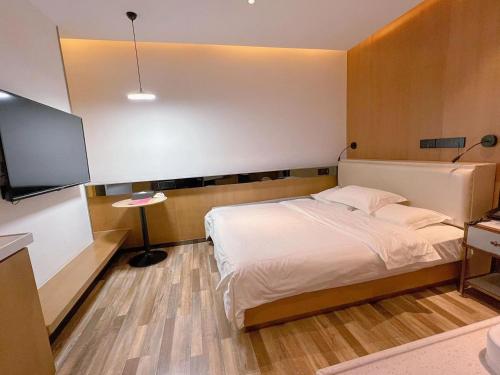 a bedroom with a bed and a flat screen tv at 银座佳驿精致酒店（济阳汽车总站店） in Jiyang