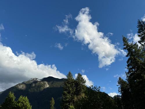 a blue sky with clouds and trees in front of a mountain at InnTowne Motel II in Hope