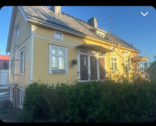 une maison jaune avec un porche et une porte dans l'établissement Yksiö lähellä Kupittaa Rautatieasemaa Turku, à Turku