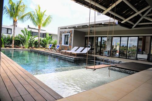 uma piscina com um baloiço numa casa em Golf View Villa em Roches Noires