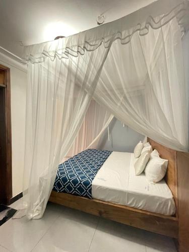 a bedroom with a canopy bed with white curtains at Alexandria Suites rooms in Kampala