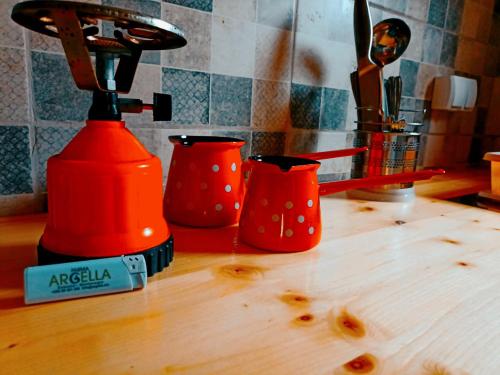 an orange blender on a wooden counter with two red cups at Argella Farm House in Bar