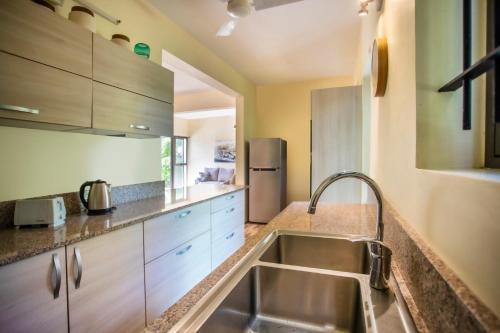 a kitchen with a sink and a refrigerator at Beach Bliss Bungalow in Rivière Noire