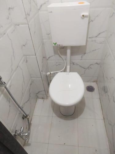 aseo blanco en un baño con paredes de mármol en Solis Stay, en Solapur