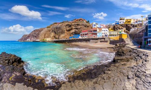 a beach with colorful buildings and the ocean at The Home E&N in Gáldar