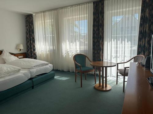 pokój hotelowy z łóżkiem, stołem i krzesłami w obiekcie ST Hotel w mieście Reichertshofen