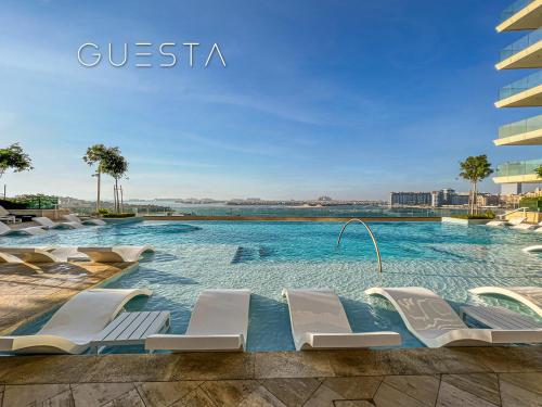 a swimming pool with white lounge chairs in a building at Emaar Beachfront - Beach Vista Tower, Dubai Marina in Dubai
