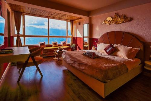 a bedroom with a bed and a desk and a window at Himalayan Hues in Gangtok