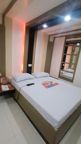 1 dormitorio con 1 cama blanca grande y espejo en Hotel Sogo Santolan, en Manila