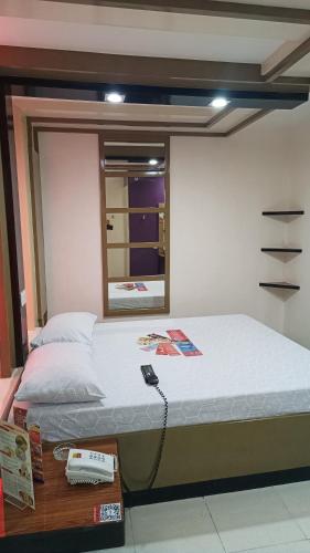 Un dormitorio con una cama con un teléfono. en Hotel Sogo Santolan, en Manila