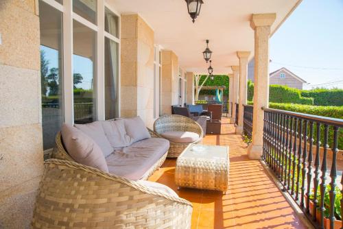a porch with a couch and chairs on a balcony at Villa Covelo in Poio