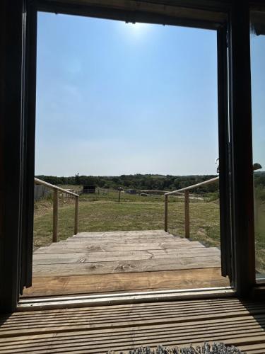 a view from a window of a wooden boardwalk at Swallowfield Glamping- Lake View in Yeovil