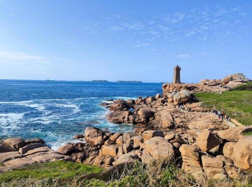 a group of people standing on the rocks near the ocean at Maison 4 personnes - Louargat in Louargat