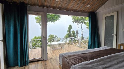 a bedroom with a bed and a balcony with a view at Instaview Kanatal in Tehri-Garhwāl