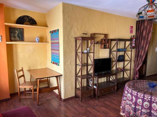 - un salon avec une table, une télévision, une table et une chaise dans l'établissement La Huella del Cuero, à Siles
