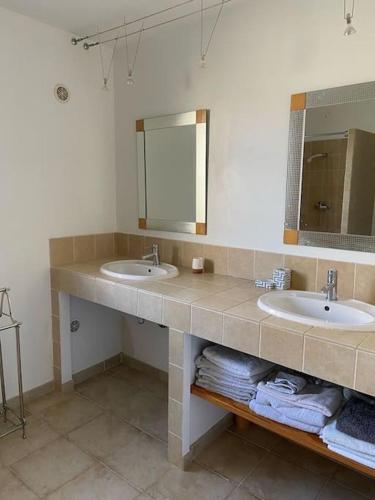 La salle de bains est pourvue de 2 lavabos, d'un miroir et de serviettes. dans l'établissement Charmant appartement St Florent T4, à Saint-Florent
