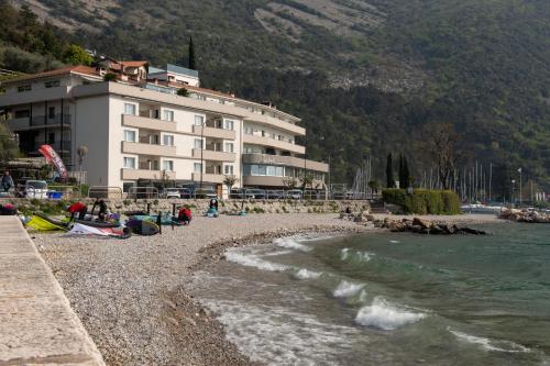 a building on a beach next to the water at Torbole Aparthotel in Nago-Torbole