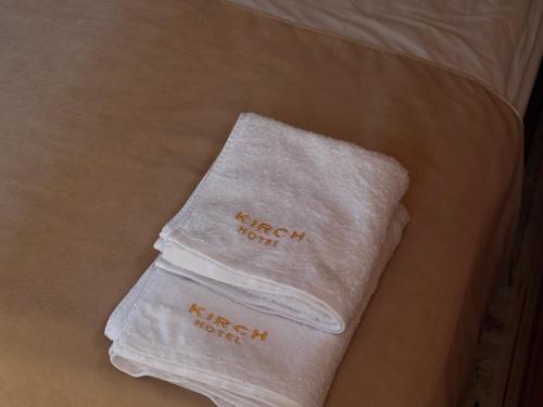 een paar witte handdoeken bovenop een bed bij Kirch Hotel & Restaurant in Goris