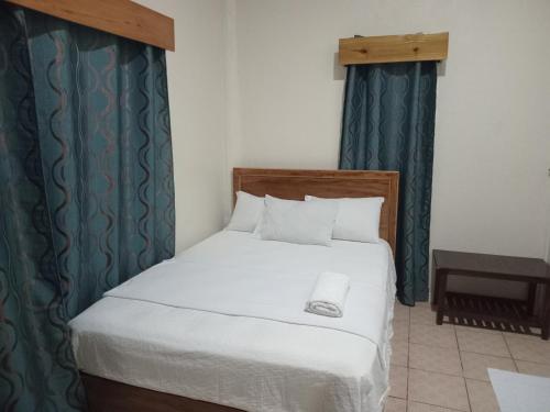 Schlafzimmer mit einem weißen Bett und grünen Vorhängen in der Unterkunft Sunset Lodge in Savusavu