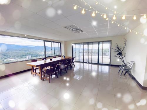 a dining room with a table and chairs and large windows at 巨缿民宿巨象民宿 in Sanyi