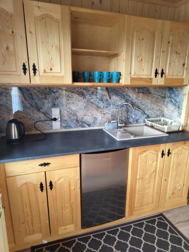 a kitchen with wooden cabinets and a sink at Pokoje gościnne Jawor in Bukowina Tatrzańska