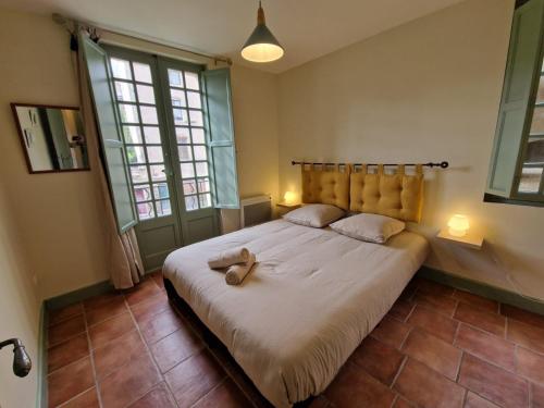 a bedroom with a large bed in a room with two windows at Le Logis Saint Roch in Pézenas