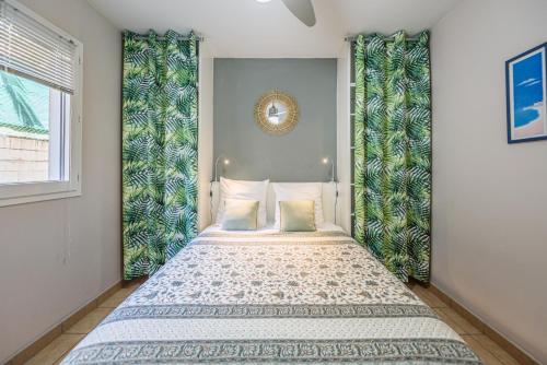a bedroom with a bed with green curtains at Le jardin des Tuit Tuit * Vue Mer * Cozy in Saint-Leu
