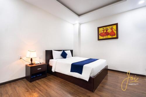 a bedroom with a bed and a night stand with a lamp at Joi Hospitality - Central in Vung Tau