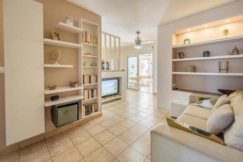 a living room with a couch and a tv at Le jardin des Tuit Tuit * Vue Mer * Cozy in Saint-Leu