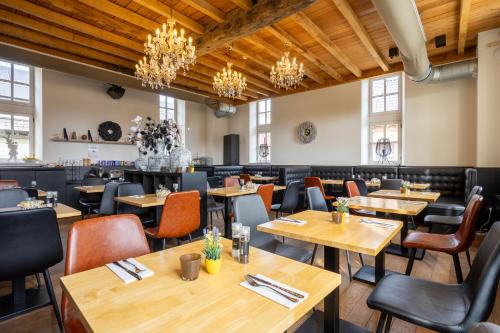 um restaurante com mesas e cadeiras de madeira e lustres em Hotel De Boskar Peer em Peer