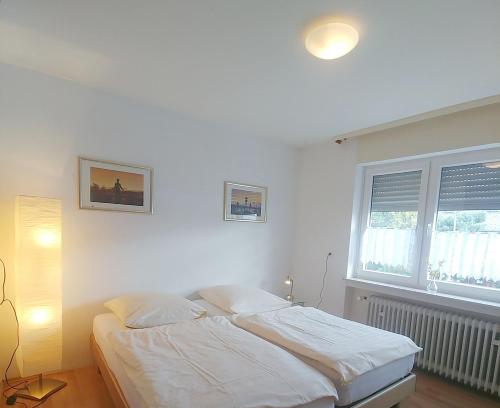 a white bedroom with a bed and a window at Haus Abendsonne Obergeschoss klein in Koblenz