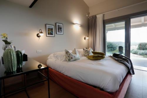 a bedroom with a large bed with a large window at Agriturismo Le Piccole Macìe in Magliano in Toscana
