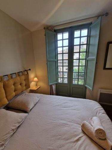 une chambre avec un grand lit et une grande fenêtre dans l'établissement Le Logis Saint Roch, à Pézenas