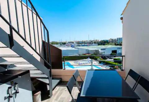 d'un balcon avec une table et une vue sur la piscine. dans l'établissement Le Solarium - Piscine - 7 pers - Centre Port, au Cap d'Agde