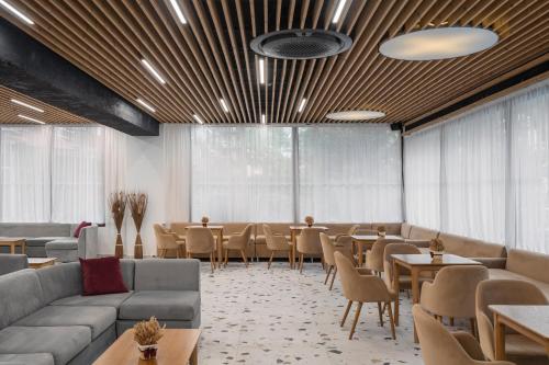 a restaurant with couches and tables and chairs and windows at Grand Hotel Sunny Beach - All Inclusive in Sunny Beach
