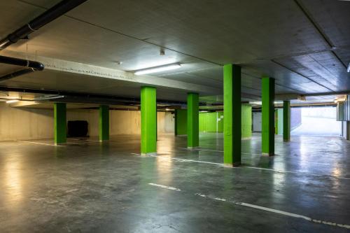 an empty parking lot with green columns in an empty parking garage at Hotel De Boskar Peer in Peer
