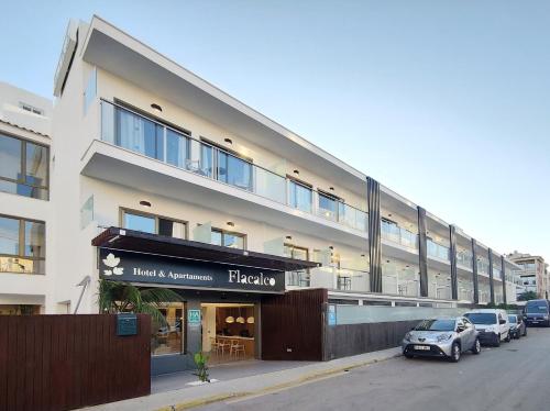 a large building with cars parked in front of it at Flacalco Hotel & Apartments in Cala Ratjada