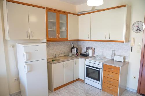 cocina con armarios blancos y nevera blanca en Stella's Apartment, en Alexandroupoli