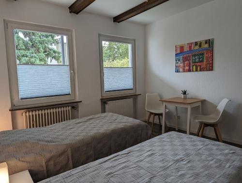 Gästehaus Koblenz Obergeschoss في فالندار: غرفة نوم بسريرين وطاولة ونوافذ