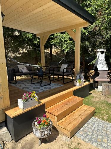 a wooden gazebo with benches and flowers at Domki z jacuzzi Pasja I in Mizerna
