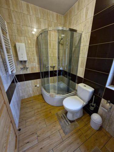 a bathroom with a shower and a toilet and a tub at Żwirowa Góra - Domki nad Narwią in Tykocin