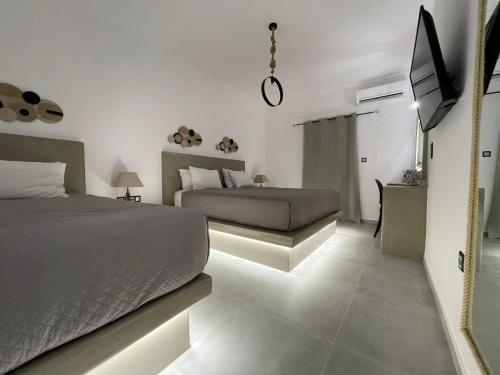 a bedroom with two beds and a flat screen tv at Zoumis Residence in Naousa