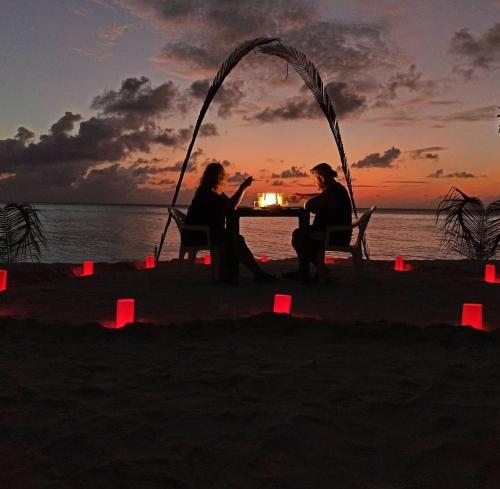 a group of three people sitting at a table on the beach at Sunnyside Inn Thoddoo in Thoddoo