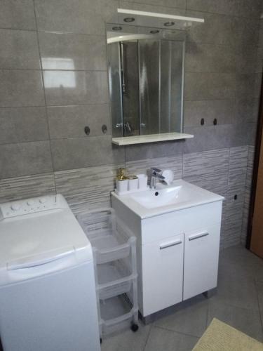 a bathroom with a sink and a toilet and a mirror at ApartmanA&J1111 in Kaštela