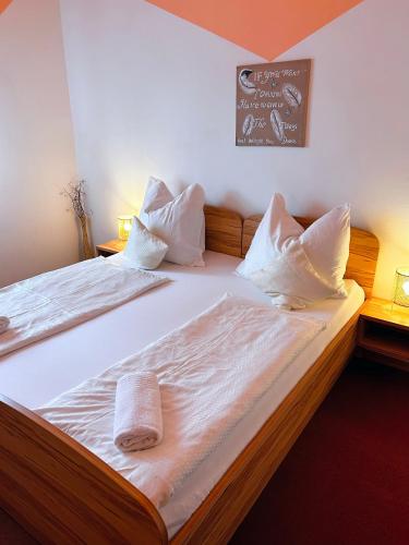 a bedroom with a bed with white sheets and pillows at Frühstückspension Elena Nicoleta Caltun in Fischamend Dorf